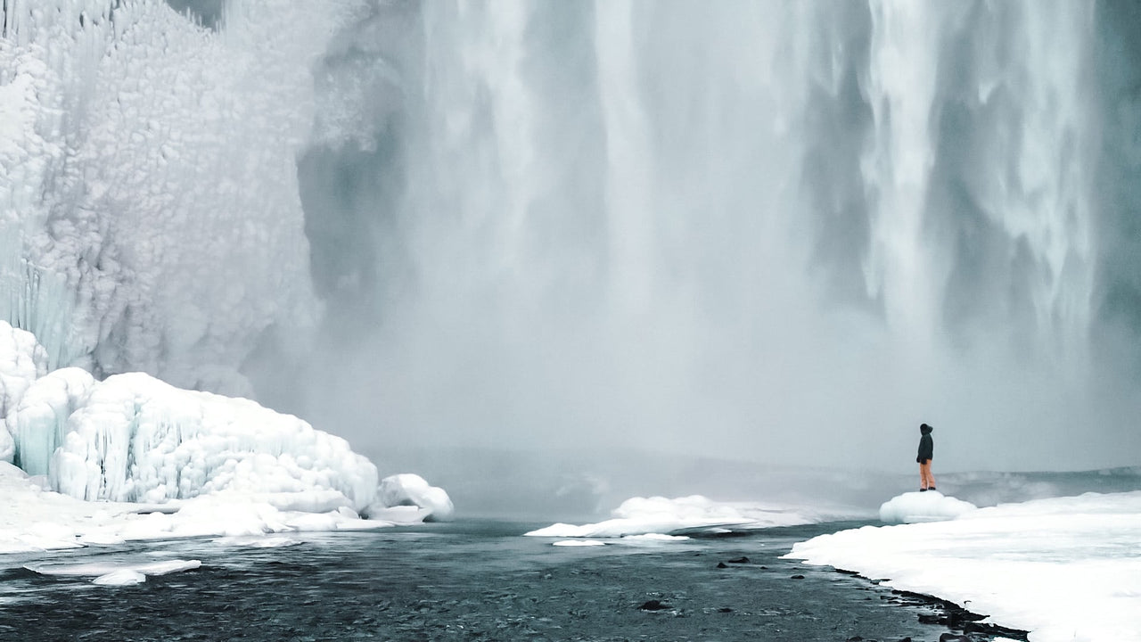 A single figure in front of a frozen waterfall in Iceland