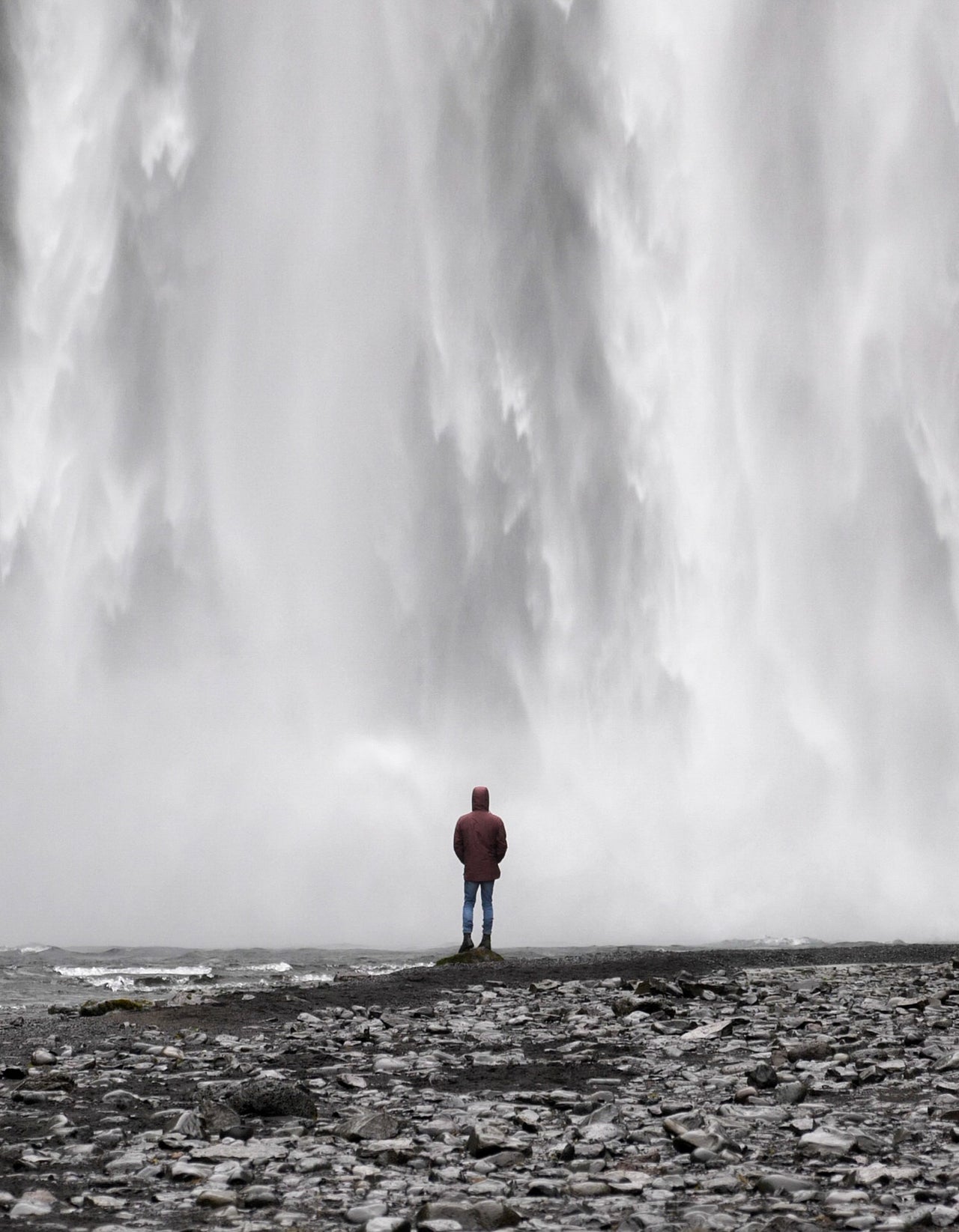 A figure at the base of a waterfall in Iceland